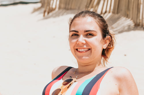 person smiles while laying back on the beach