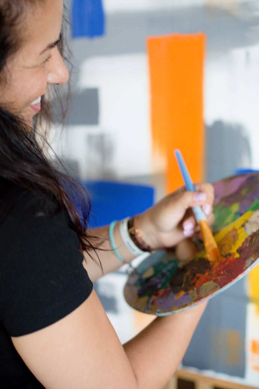 person smiles while painting with a paint pallet