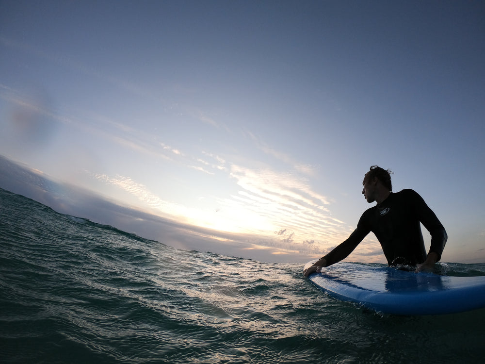 person standing in wavy water holding a surfboard