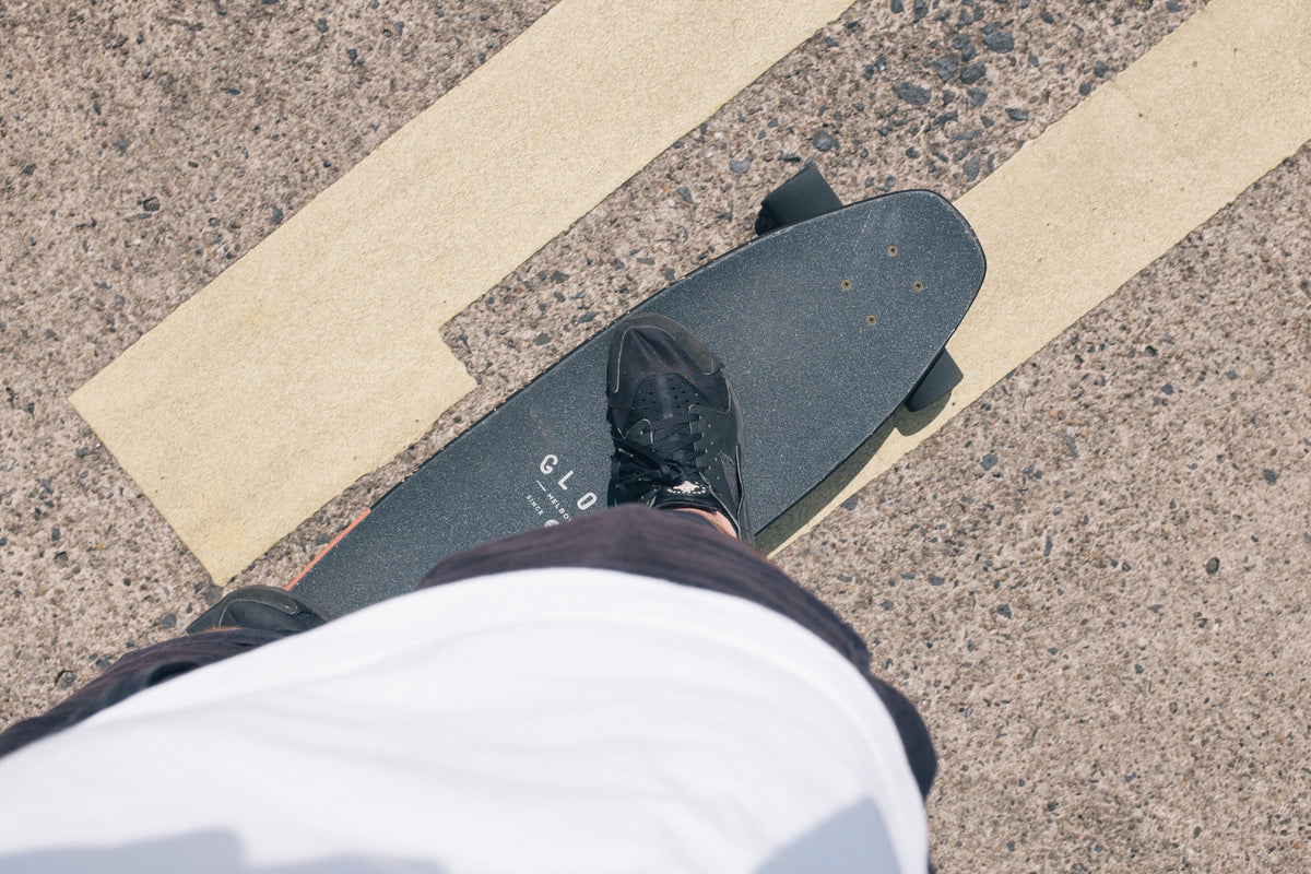 person standing on a black skateboard on a paved road