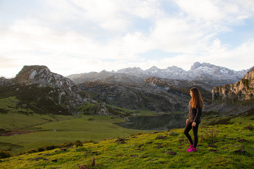 person stands and looks out to lush green mountains