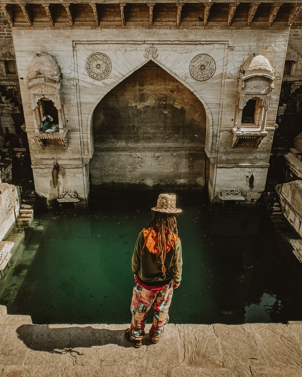 person stands at the edge of a rock pond