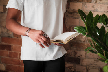 person stands by a brick wall and holds a book open