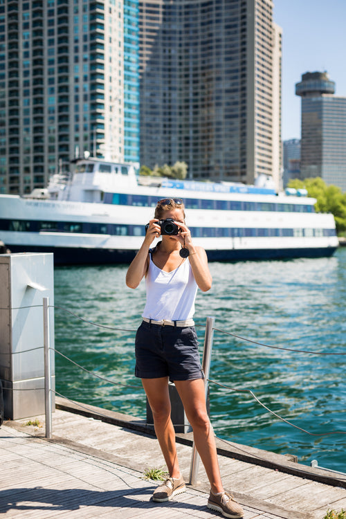 person stands by waterfront and holds camera up to take a picture