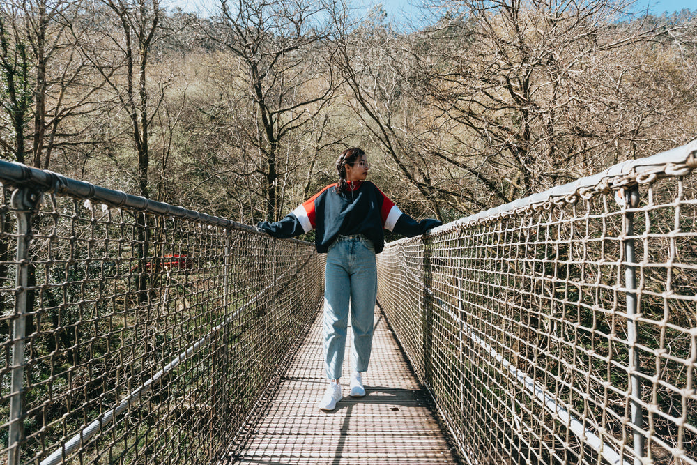 person stands on a bridge with one hand on each railing