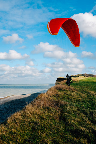 person stands on a grassy hill kite surfing