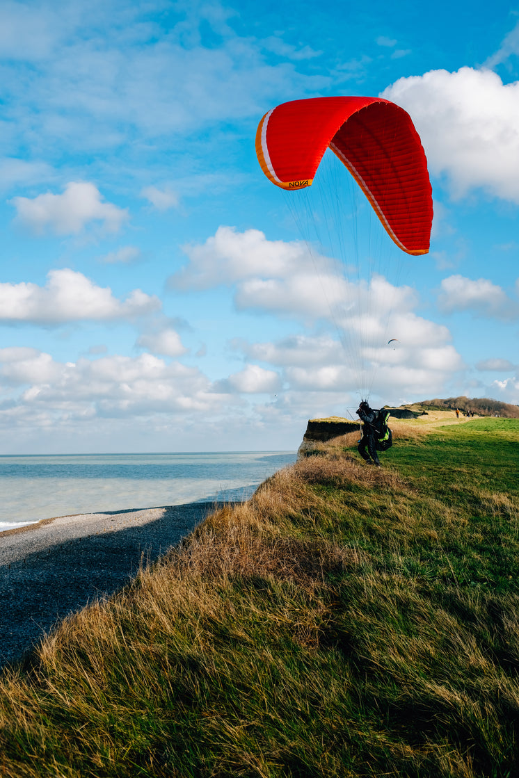 Person Stands On A Grassy Hill Kite Surfing