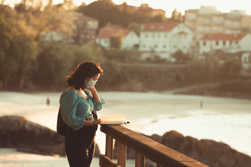 person stands on a pier and reads a book