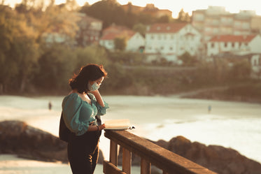 person stands on a pier and reads a book