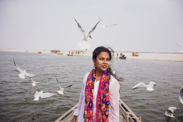 person stands on boat with birds all around them