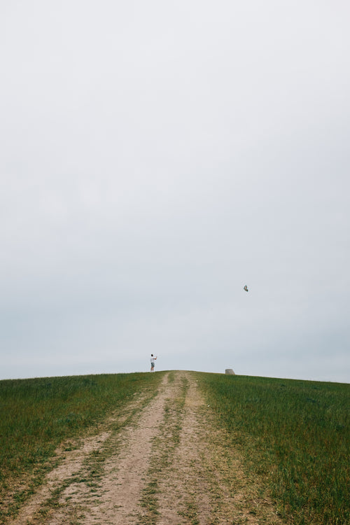 person stands on hill and flies a kite