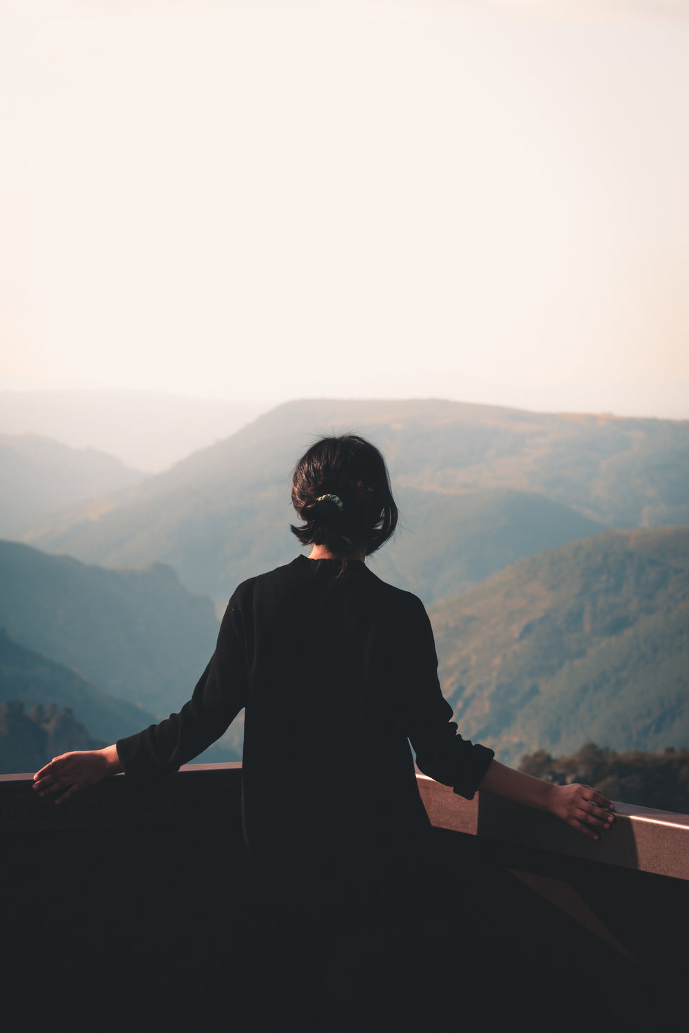 person stands on look out at a hazy mountain view