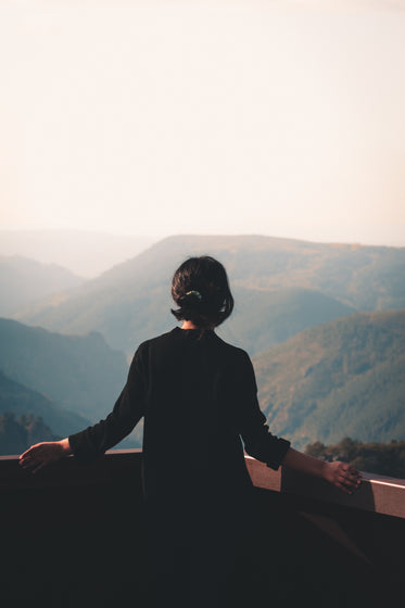 person stands on look out at a hazy mountain view