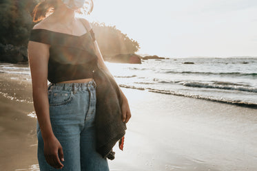 person stands on sandy beach looking out to the water