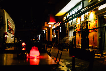 person stands outside a line of restaurants at night