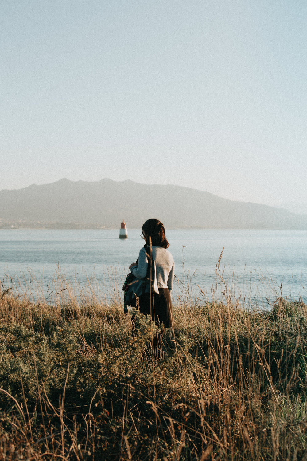 person stands with their head down in tall grass