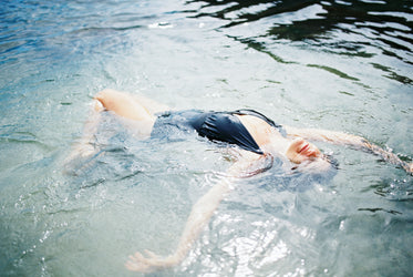 person swims on their back in clear water