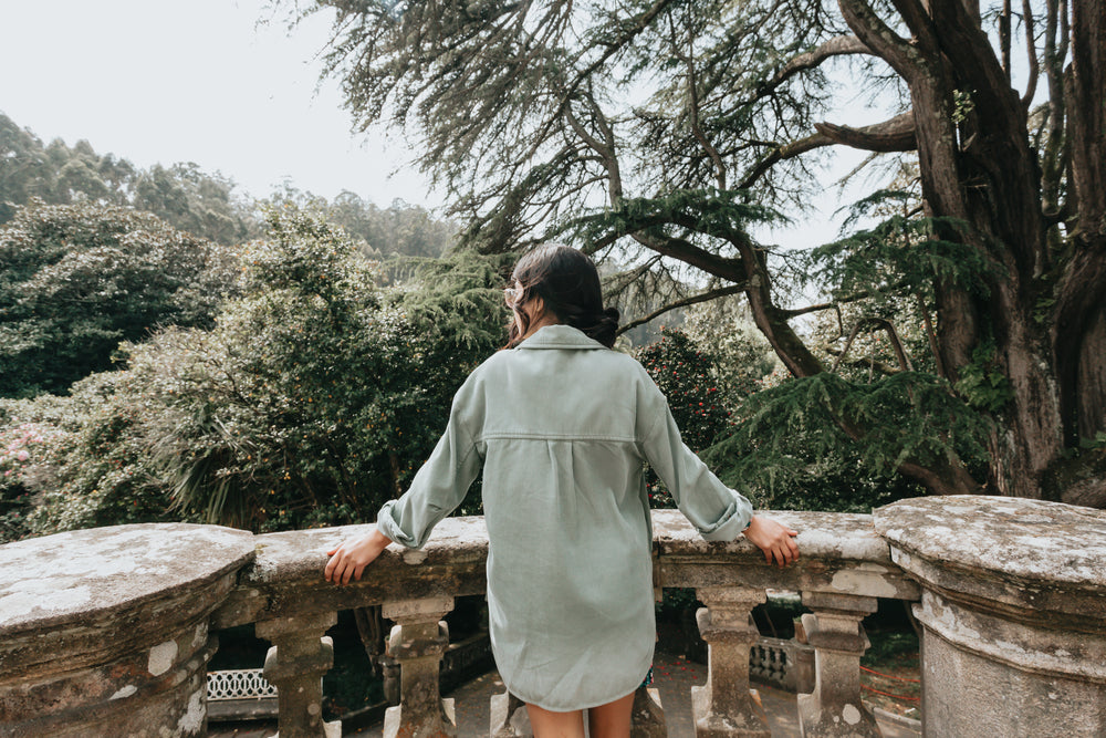 person takes in a forest view from a cement balcony