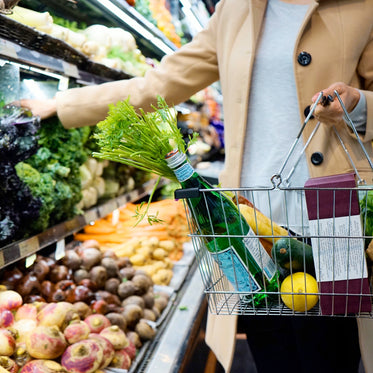 person uses a silver shopping basket to shop for groceries