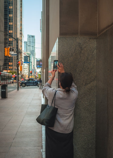 person uses their cell phone to talk a picture of a building