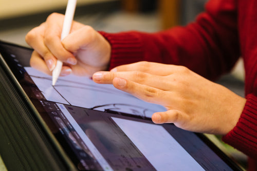 person using pencil to design on tablet