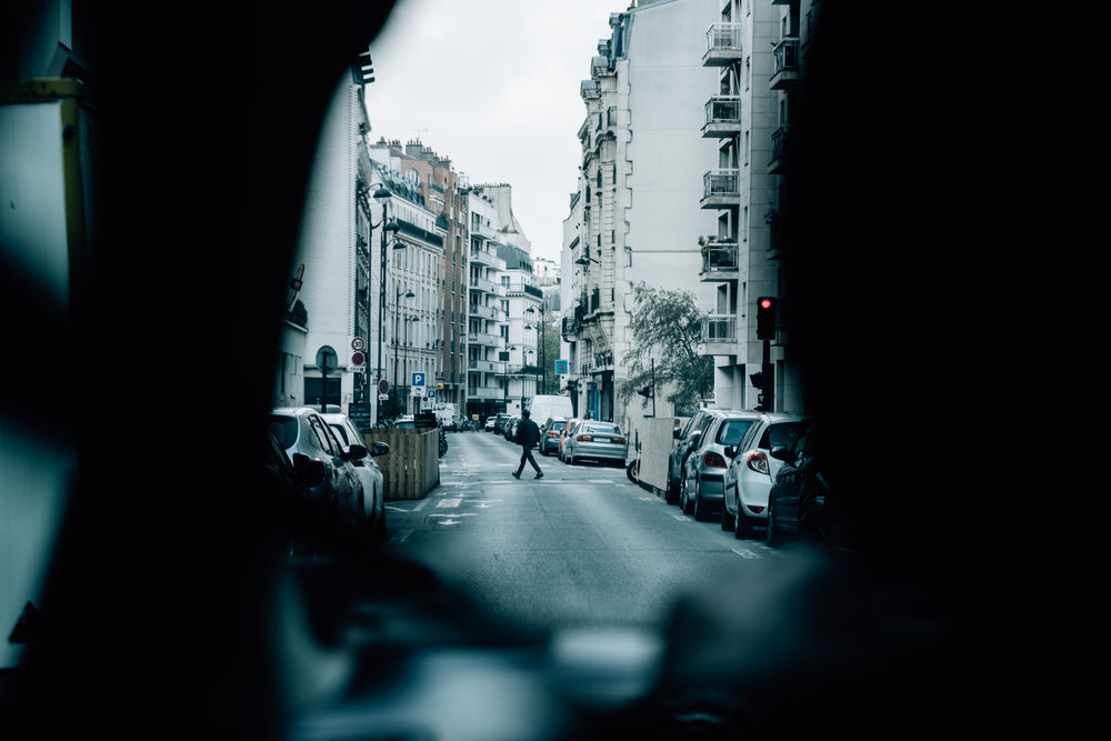 person walking across a car lined street in an urban setting