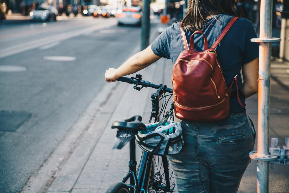 pessoa empurrando a bicicleta na calçada