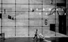 person walking by large grid window in black and white