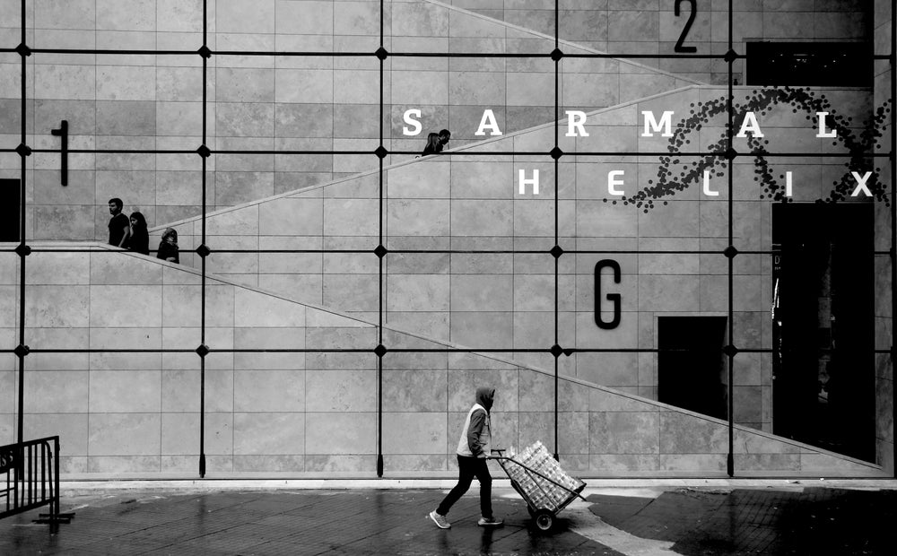 person walking by large grid window in black and white