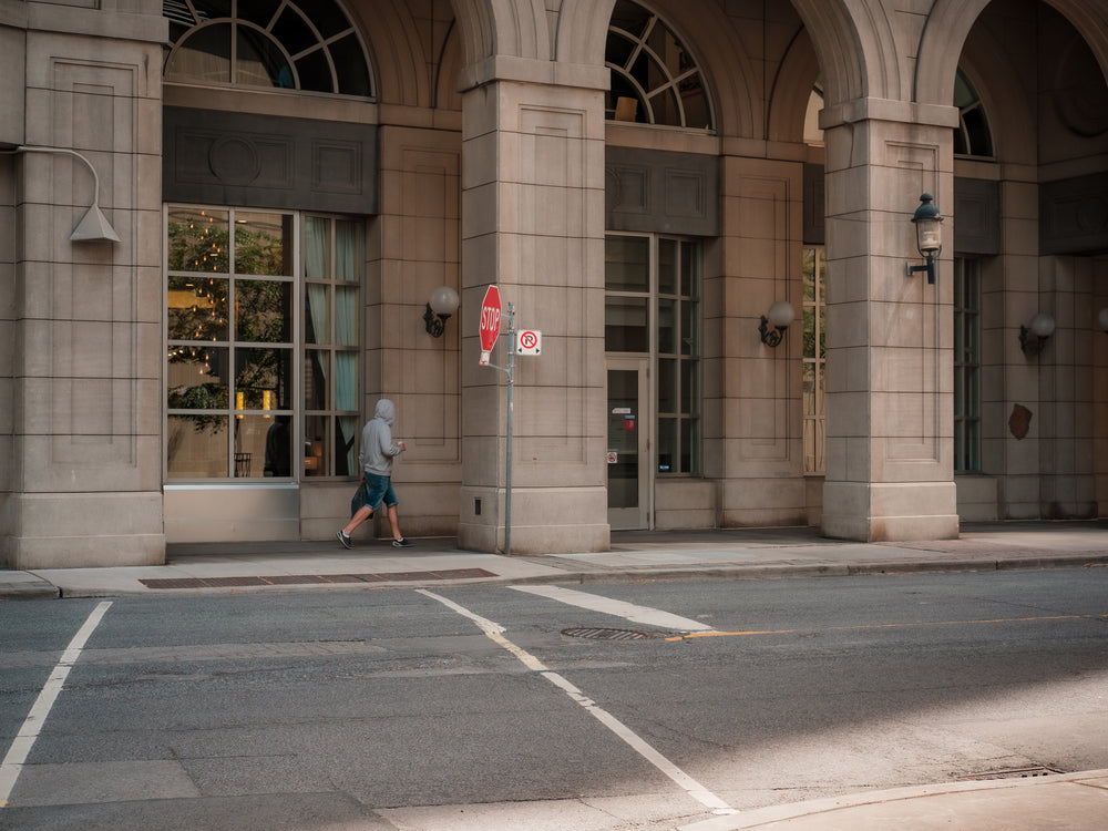 person walking under a city building with tall archways