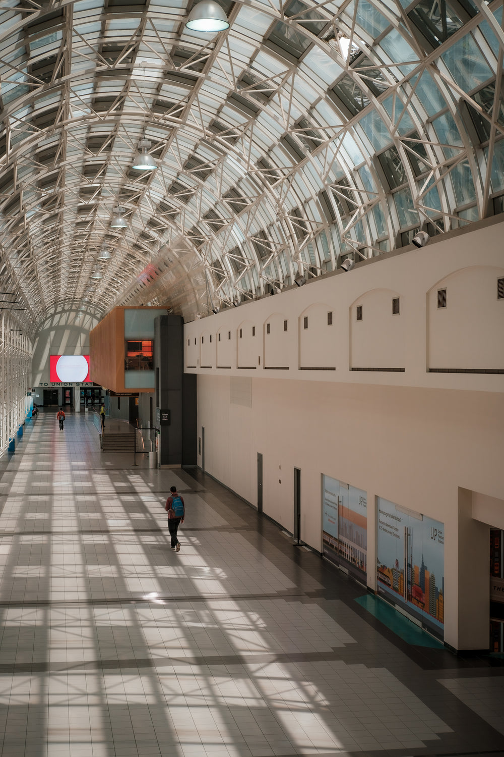 person walks down a wide atrium with a curved ceiling