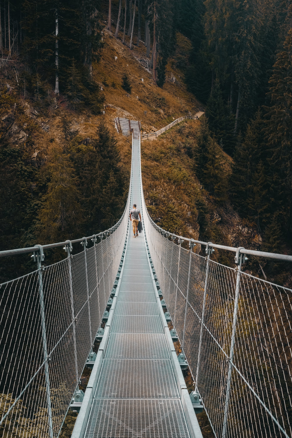 person walks on a metal suspension bridge
