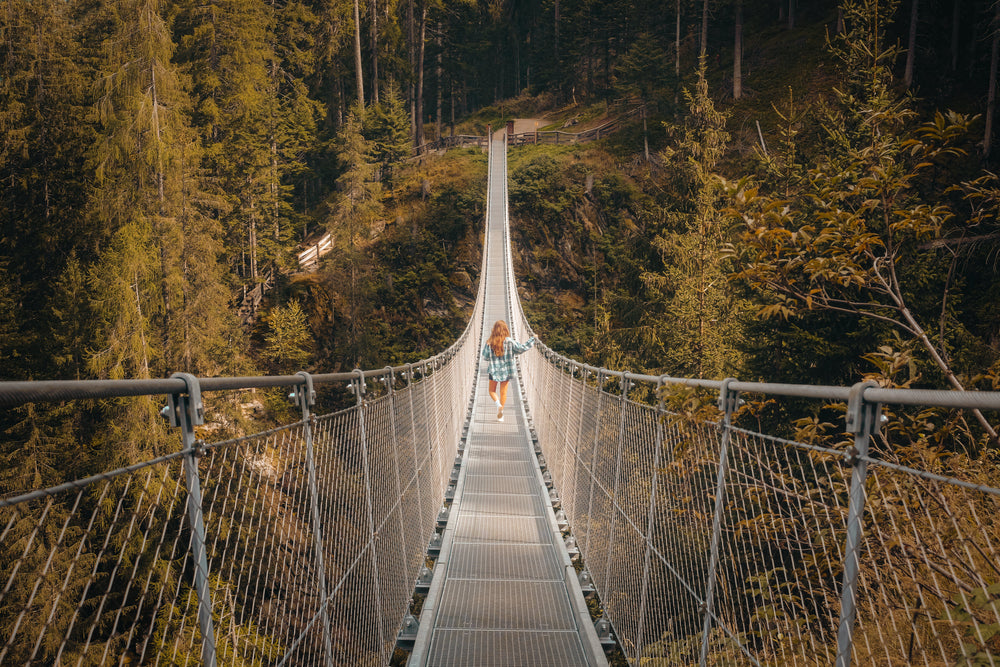 person walks to the otherside of a metal suspension bridge