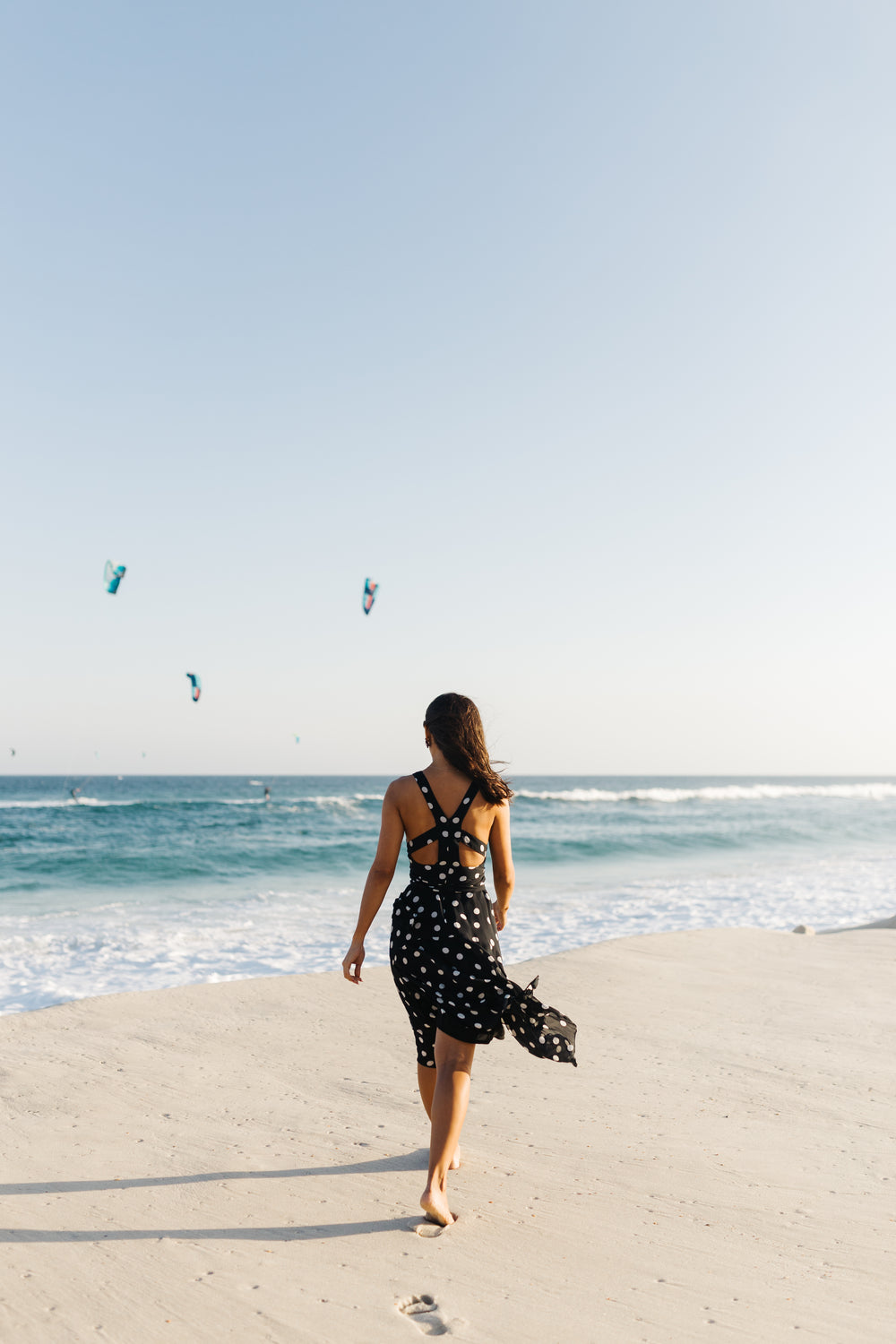 person walks towards the water on a sandy beach