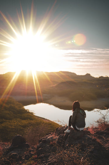 person watches the sunset over the distant mountains