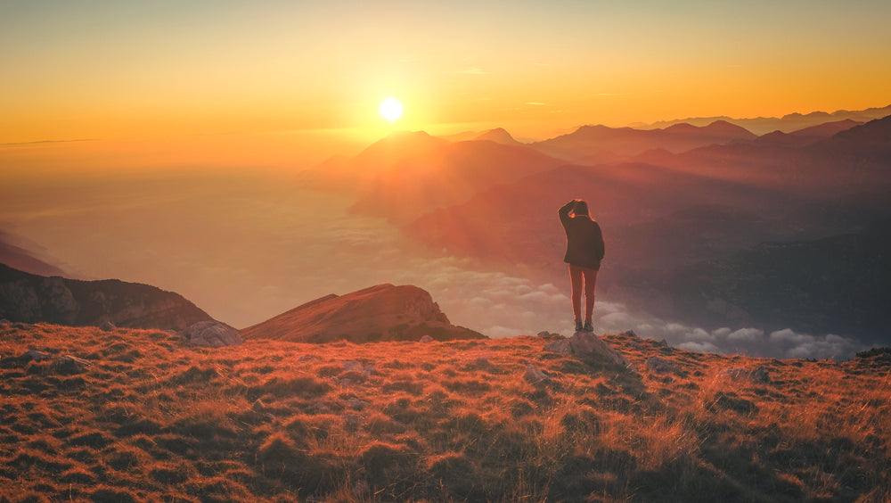 person watching sunset above the clouds