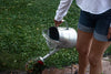 person waters plants with a watering can