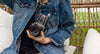 person wearing a jean jacket and holding film camera