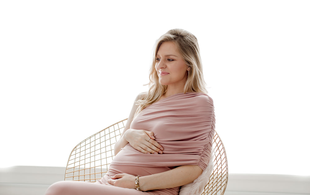 person wearing pink sits while holding their belly