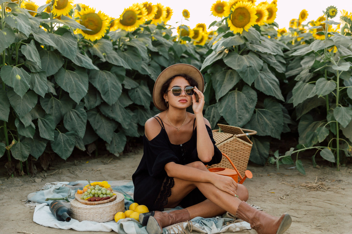 person wearing sunglasses enjoys a picnic by a sunflower field
