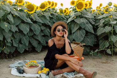 person wearing sunglasses enjoys a picnic by a sunflower field