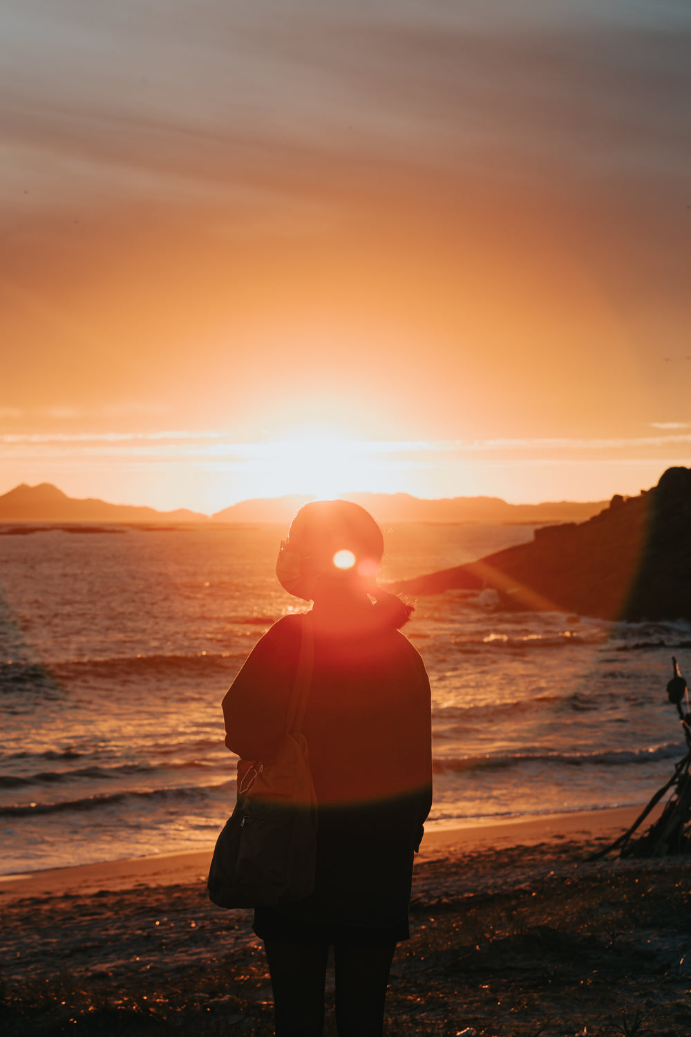 person wears a facemask and takes in a beautiful sunset