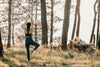 person with arms reaching high does yoga in a forest
