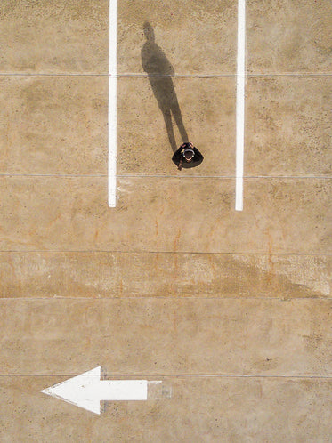 person with long shadow in parking spot