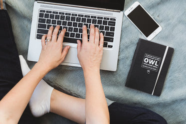 person working on laptop with phone and notebook beside