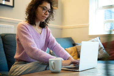 person works from couch with a coffee mug nearby