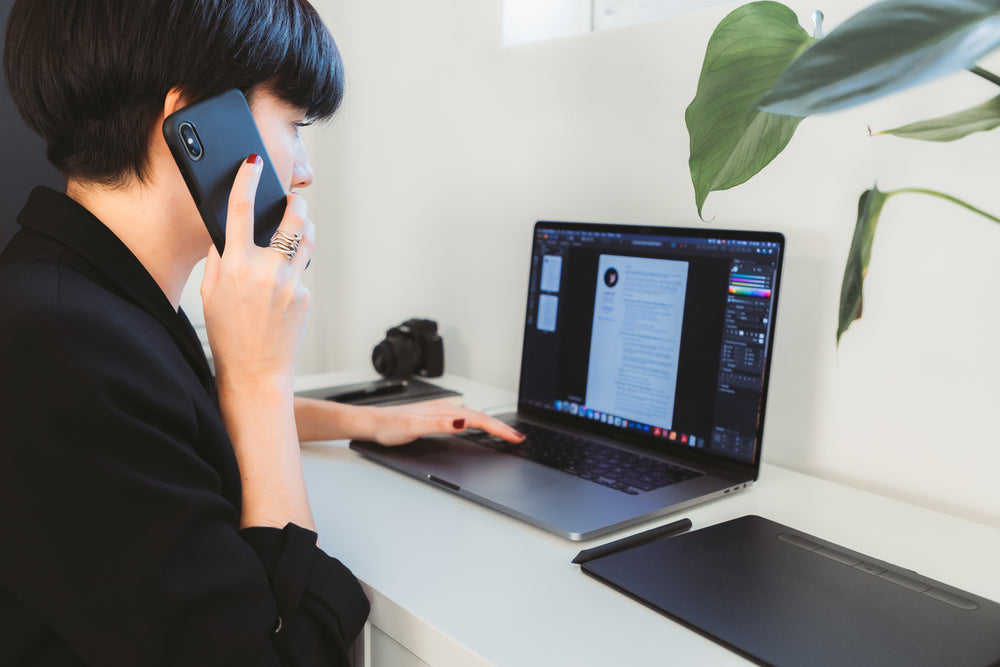 person works on a open laptop while on the phone