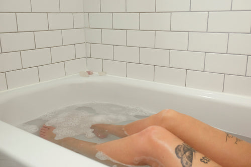 persons bare legs in a bathtub full of water