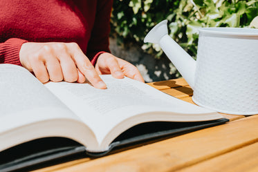 persons hand points to text in a open book laying in a table