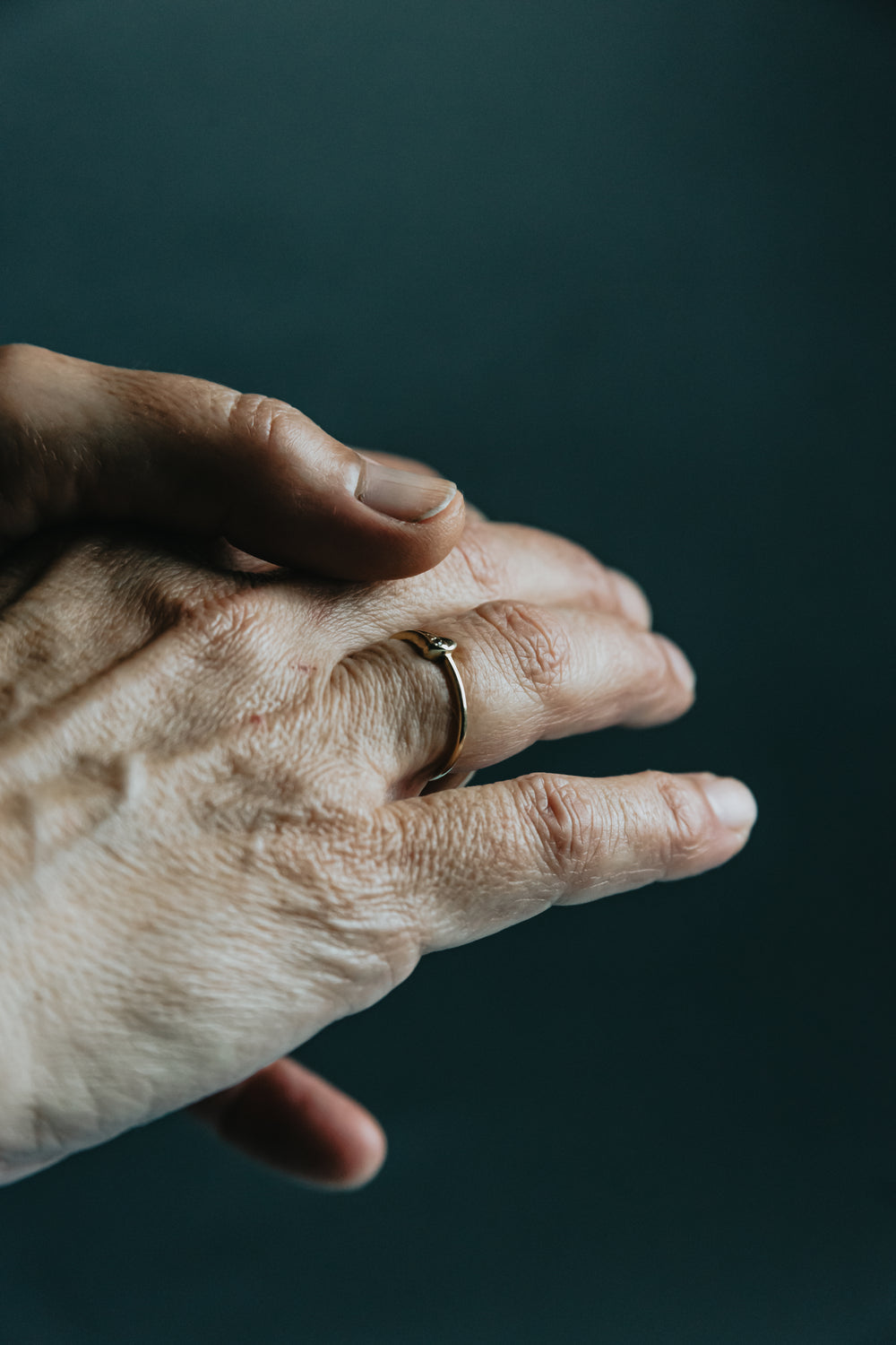 persons hand with a ring on it against blue